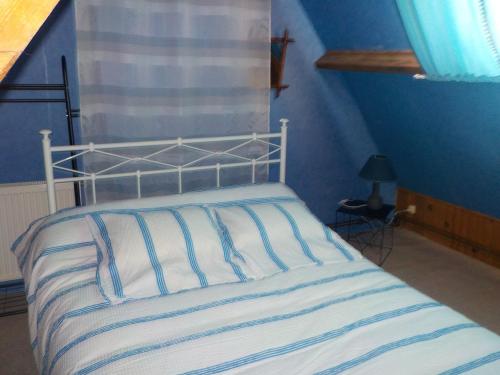 Bett mit einer weißen und blauen gestreiften Bettdecke in der Unterkunft 618 rue de l argiliere Helfaut 62570 