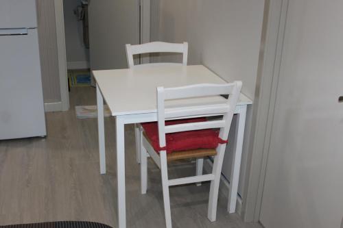 a white table with two chairs and a refrigerator at Self contained Studio with Ensuite, WIFI & Kitchenette in Auckland