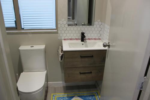 a bathroom with a white toilet and a sink at Self contained Studio with Ensuite, WIFI & Kitchenette in Auckland