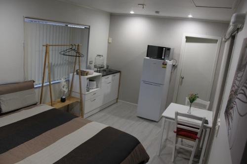 a bedroom with a bed and a refrigerator and a table at Self contained Studio with Ensuite, WIFI & Kitchenette in Auckland