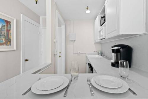 a white kitchen with two plates and glasses on a counter at Tropicals of Palm Beach in Palm Beach
