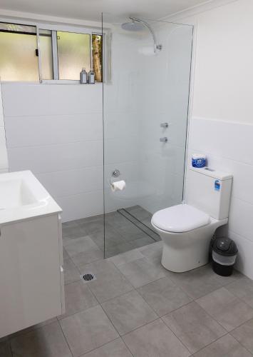 a bathroom with a toilet and a glass shower at Aston Hill Motor Lodge in Port Macquarie