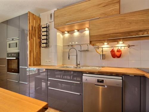 une cuisine avec des appareils en acier inoxydable et des armoires en bois dans l'établissement Chalet spacieux sur les pistes avec cheminée et WiFi - FR-1-455-242, à La Plagne Tarentaise