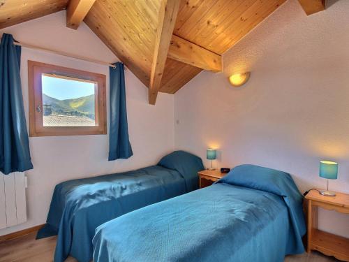 - une chambre avec 2 lits bleus et une fenêtre dans l'établissement Chalet spacieux sur les pistes avec cheminée et WiFi - FR-1-455-242, à La Plagne Tarentaise