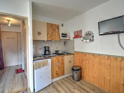 Il comprend une cuisine avec des placards en bois et une télévision murale. dans l'établissement Charmant studio à Morzine - 4 pers, 19m², proche navettes gratuites pour Avoriaz, balcon, parking - FR-1-524-122, à Morzine