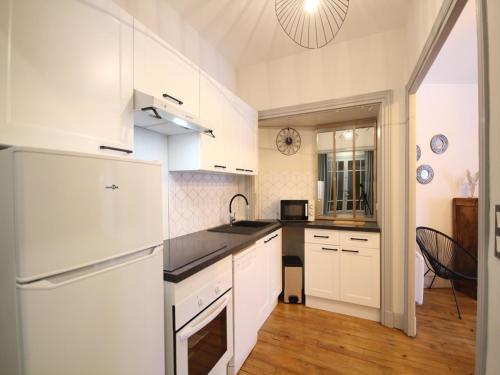 une cuisine avec des armoires blanches et un comptoir noir dans l'établissement Hyper-centre Mont-Dore, bel appart T3 Bis, 7 pers, tout équipé, vue montagne, wifi - FR-1-608-256, à Le Mont-Dore