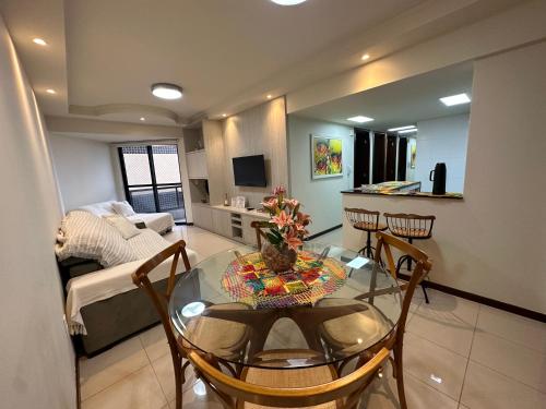 a living room with a glass table and a kitchen at Apartamento beira mar em Maceió in Maceió