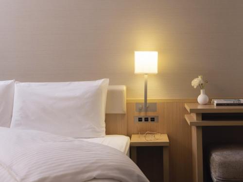 ein Schlafzimmer mit einem Bett und einer Lampe auf einem Tisch in der Unterkunft Mitsui Garden Hotel Kyoto Shinmachi Bettei in Kyoto