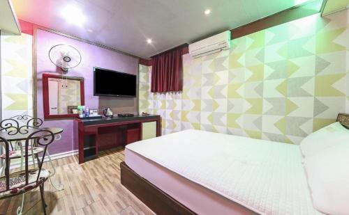 a bedroom with a bed and a desk with a mirror at Paldo Motel in Yeosu