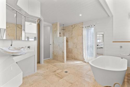 a white bathroom with a tub and a sink at A Perfect Stay - The Beach House in Lennox Head