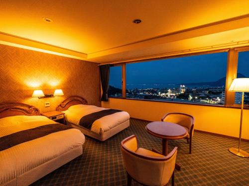 Habitación de hotel con 2 camas y ventana grande. en Yukai Resort Premium Hotel Fugetsu en Beppu
