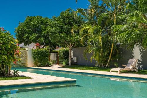 a swimming pool with a chair and palm trees at Ocean Walk - Villa near Main Beach in Byron Bay