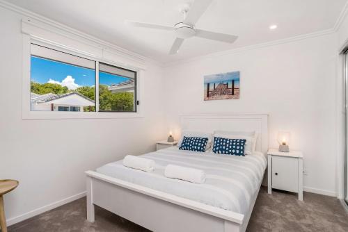 a white bedroom with a large bed and a window at Ocean Walk - villa with pool near Main Beach in Byron Bay