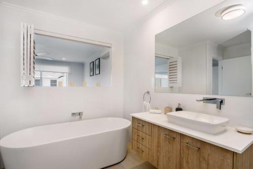 a white bathroom with a tub and a sink at Ocean Walk - villa with pool near Main Beach in Byron Bay