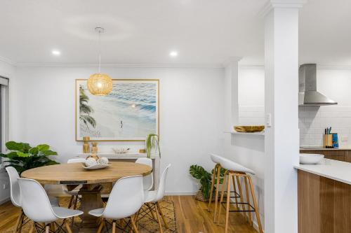 a kitchen and dining room with a wooden table and chairs at Drift - 3 BR home near town & beach with pool in Byron Bay