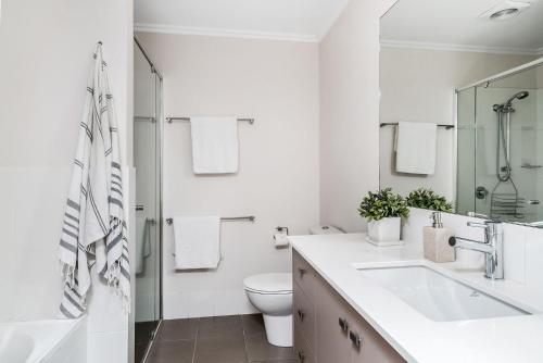 a white bathroom with a toilet and a sink at A Perfect Stay - Drift in Byron Bay