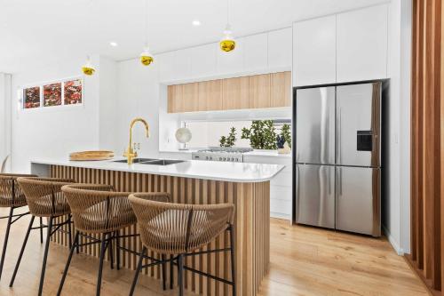 a kitchen with a large island with a stainless steel refrigerator at Haven On Hooper in Gold Coast