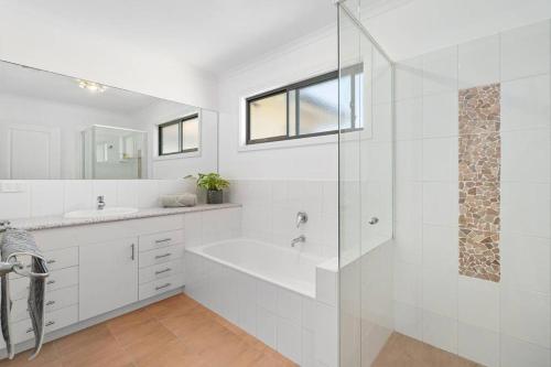 a white bathroom with a tub and a glass shower at Golden Sands Rye in Rye