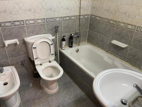 a bathroom with a toilet and a tub and a sink at AlAIN GUEST HOUSE in Al Ain