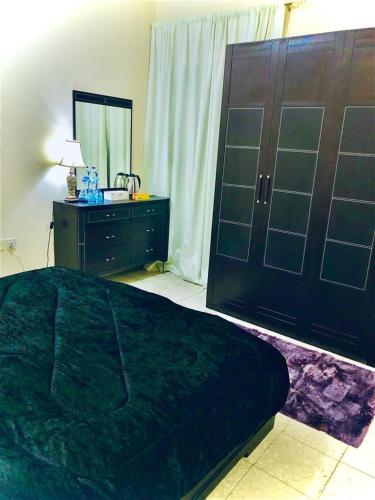 1 dormitorio con 1 cama negra grande y vestidor en AlAIN GUEST HOUSE, en Al Ain