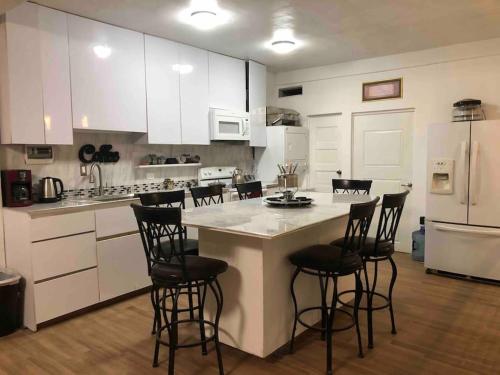 una cocina con armarios blancos y taburetes negros en Apartment in Puerto Nuevo, 