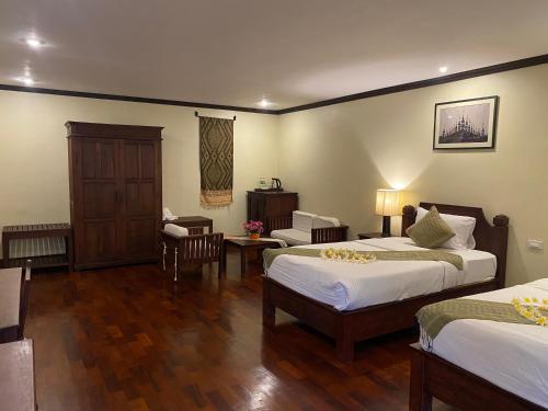 Luang Prabang Residence & Travel في لوانغ برابانغ: غرفة فندقية بسريرين وطاولة وكراسي