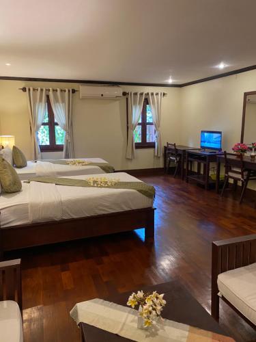 a bedroom with two beds and a table and a television at Luang Prabang Residence & Travel in Luang Prabang