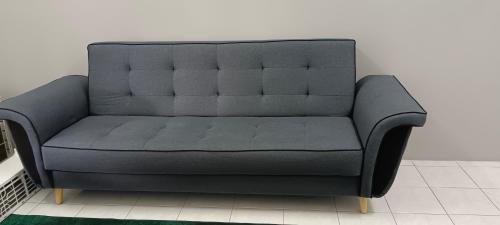 a gray couch in a room with a wall at Inap Mudah in Seri Iskandar