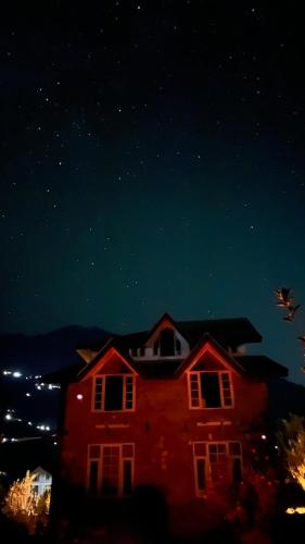 a red house at night with the stars in the sky at Flüstern Manali in Nagar