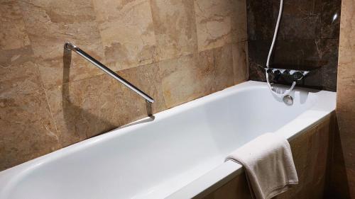 - Baño con bañera blanca y toalla en Jatinangor National Golf & Resort, en Jatinangor