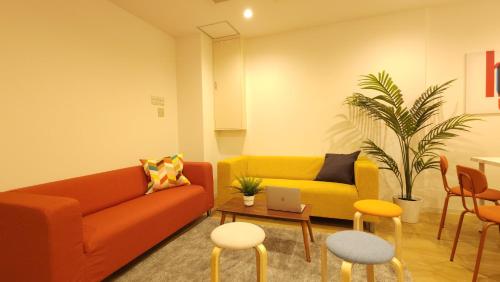 a living room with a couch and a table and chairs at Acro Capsule Hotel Namba Dotonbori in Osaka