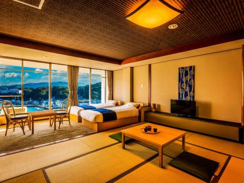 a hotel room with a bedroom with a bed and a table at Yukai Resort Premium Toba Saichoraku in Toba