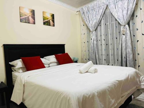 a bedroom with a large white bed with red pillows at Terry’s Cozy cottage in Germiston