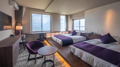 屋久島にあるTHE HOTEL YAKUSHIMA ocean & forestのベッド2台、テーブルと椅子が備わるホテルルームです。