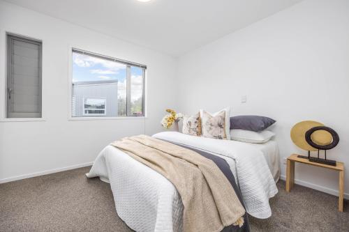 a white bedroom with a bed and a window at 3 BDR CBD Get Away in Auckland