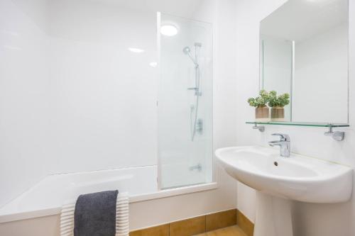 La salle de bains blanche est pourvue d'un lavabo et d'un miroir. dans l'établissement 3 BDR CBD Get Away, à Auckland