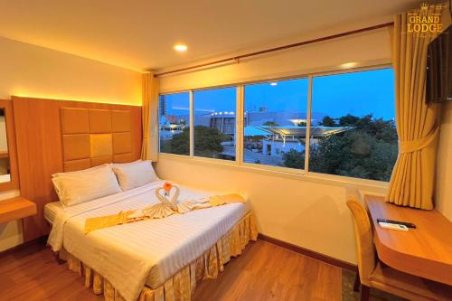 芭達雅中心的住宿－The Grand Lodge Pattaya，一间卧室配有一张床、一张书桌和一个窗户。
