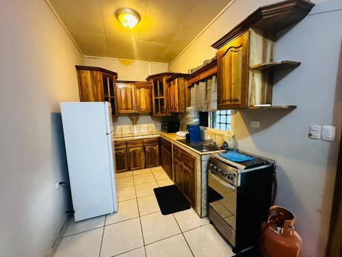 eine Küche mit Holzschränken und einem Kühlschrank in der Unterkunft Casa en Puero Cortes in Puerto Cortes