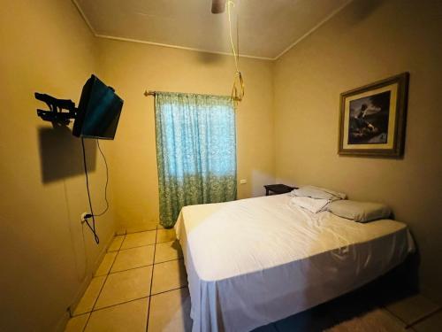 a bedroom with a bed and a tv and a window at Casa en Puero Cortes in Puerto Cortes