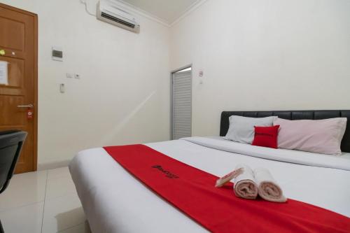 RedDoorz near Universitas Esa Unggul Bekasi Harapan Indah في بيكاسي: غرفة نوم مع سرير وفوط حمراء عليه