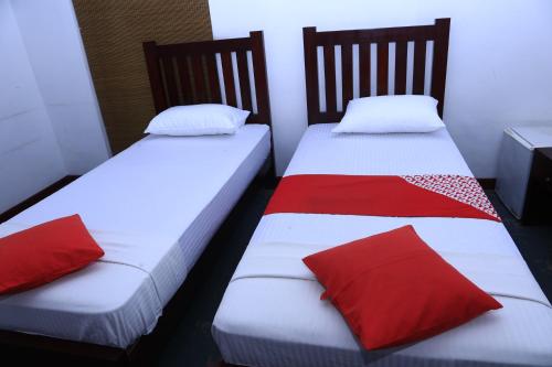 two beds with red pillows in a room at Station Garden Hotel And Resturant in Jaffna
