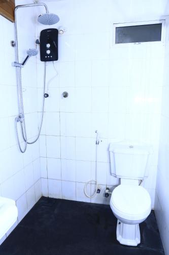 a white bathroom with a shower and a toilet at Station Garden Hotel And Resturant in Jaffna