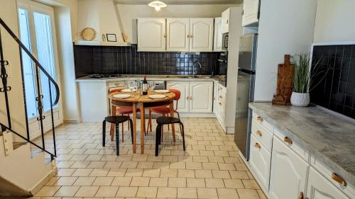 a kitchen with a table and chairs in it at La Maison d'Elise, 3 chambres, maison de caractère in Plassac