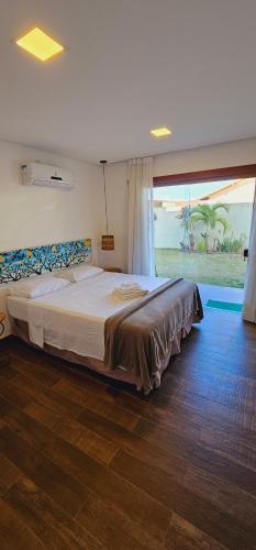 ein großes Bett in einem Schlafzimmer mit einem großen Fenster in der Unterkunft Arraia Suítes Pousada in Pipa