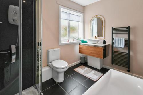 a bathroom with a toilet and a sink and a mirror at Blacksand sea view cottage in Aberdour