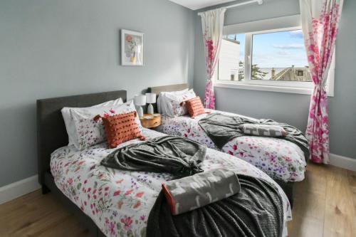 two beds in a room with a window at Blacksand sea view cottage in Aberdour