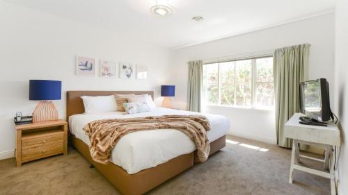 Un dormitorio con una cama y un televisor y una ventana. en Boutique Stays - Brighton Abode, en Melbourne