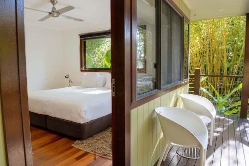 a bedroom with a bed and chairs on a balcony at A Perfect Stay - Blue Bliss House and Studios in Byron Bay