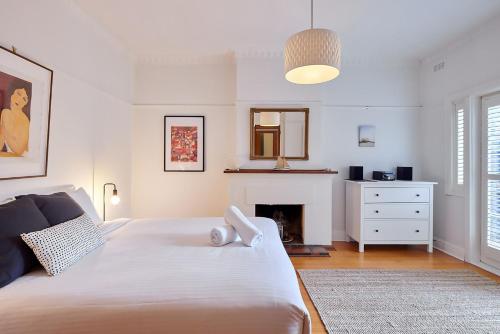 a bedroom with a large white bed and a fireplace at Boutique Stays - Mordi Beach House in Mordialloc