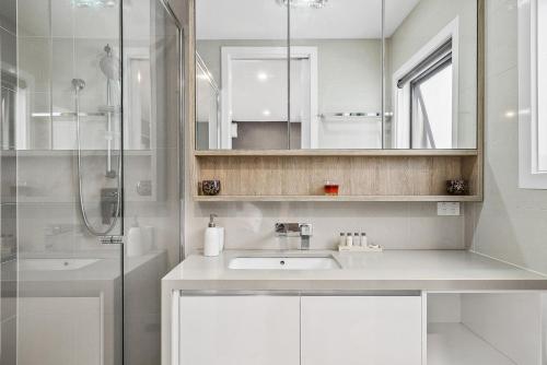 a white bathroom with a sink and a shower at Boutique Stays - Edinburgh Place in Melbourne